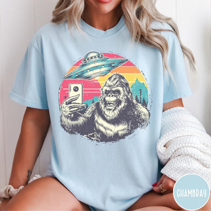 Comfort Colors tee in Chambray featuring retro Bigfoot selfie graphic with a UFO and sunset mountain background