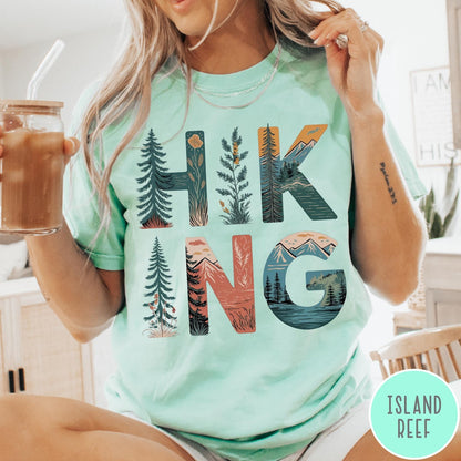 Comfort Colors tee in Island Reef featuring nature graphic with trees and mountains inside the word Hiking
