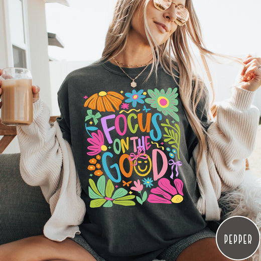 Comfort Colors tee in Pepper featuring positivity typography and floral collage graphic with a smiley face.
