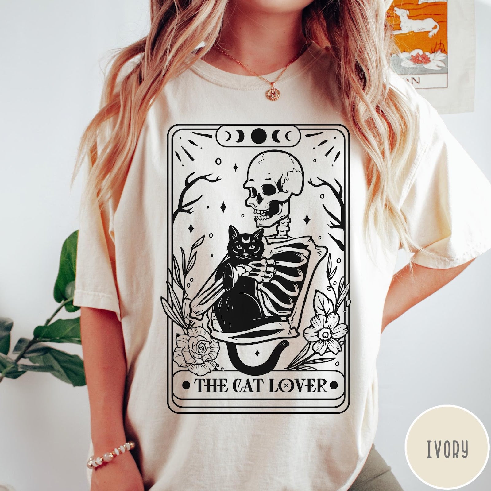 Comfort Colors tee in Ivory featuring tarot style graphic of a skeleton holding a black cat