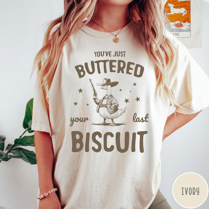 Comfort Colors tee in Ivory featuring western graphic style cowboy goose holding a revolver with star accents