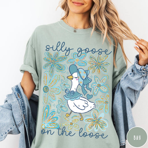 Comfort Colors tee in Bay featuring whimsical graphic style with a goose wearing a bonnet and floral border