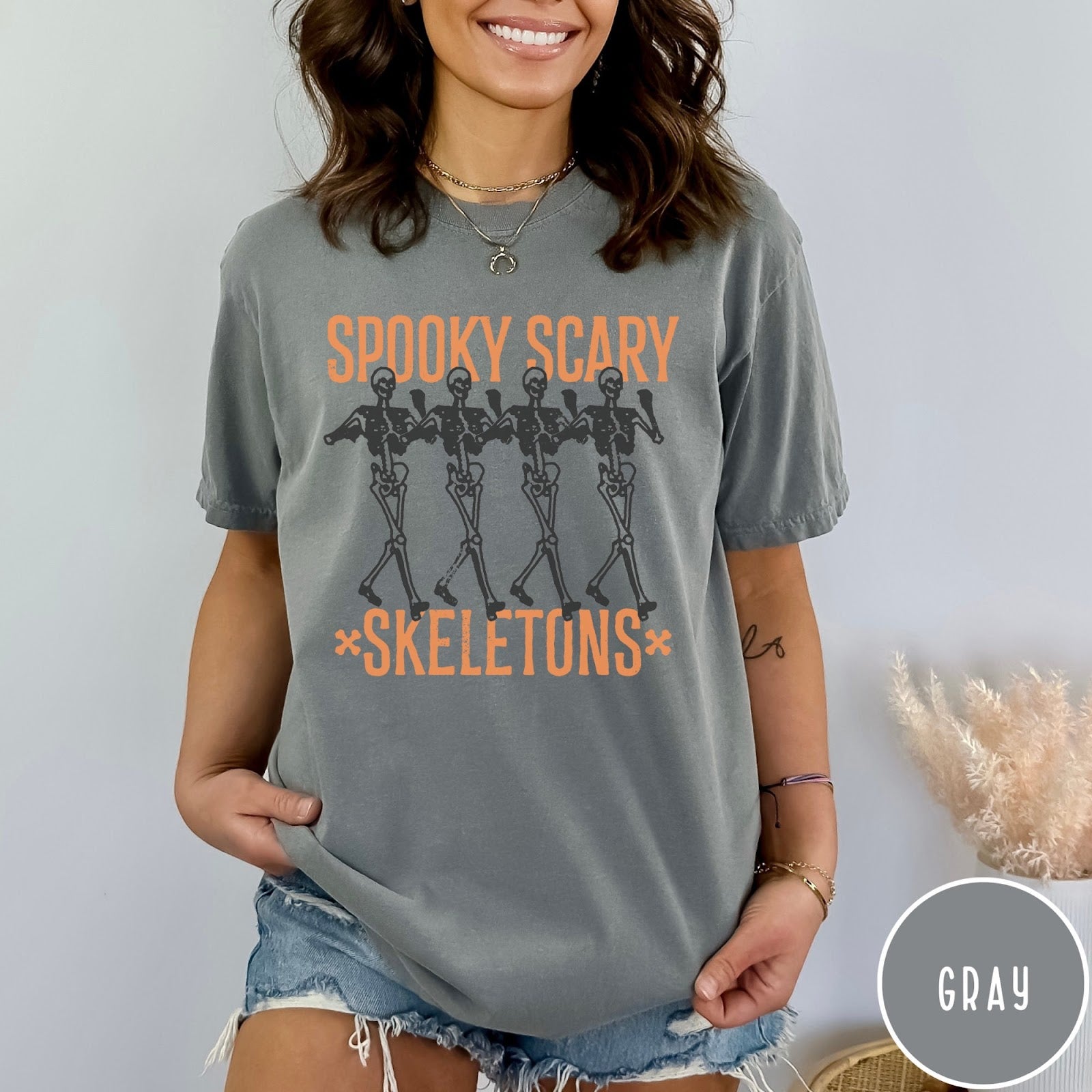 Comfort Colors tee in Gray featuring dancing skeletons graphic with Spooky Scary Skeletons text in orange