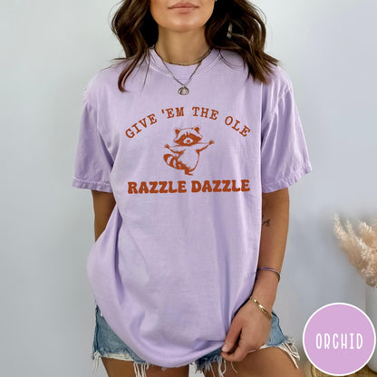Comfort Colors tee in Orchid featuring whimsical raccoon graphic with Give Em The Ole Razzle Dazzle text