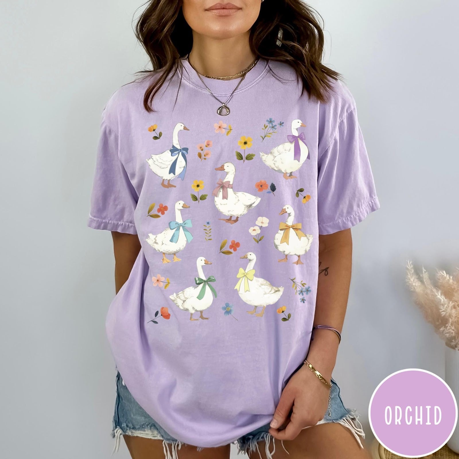 Comfort Colors tee in Orchid featuring vintage style graphic of several white geese wearing colorful bows and flowers