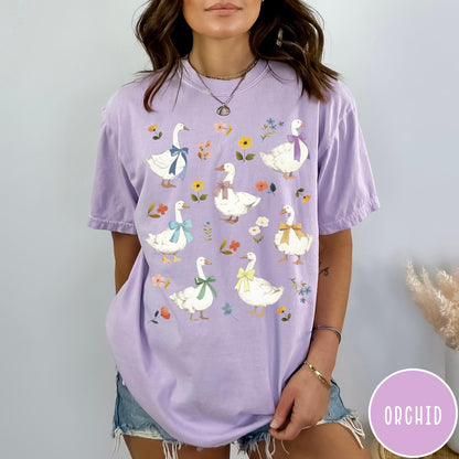 Comfort Colors tee in Orchid featuring vintage style graphic of several white geese wearing colorful bows and flowers
