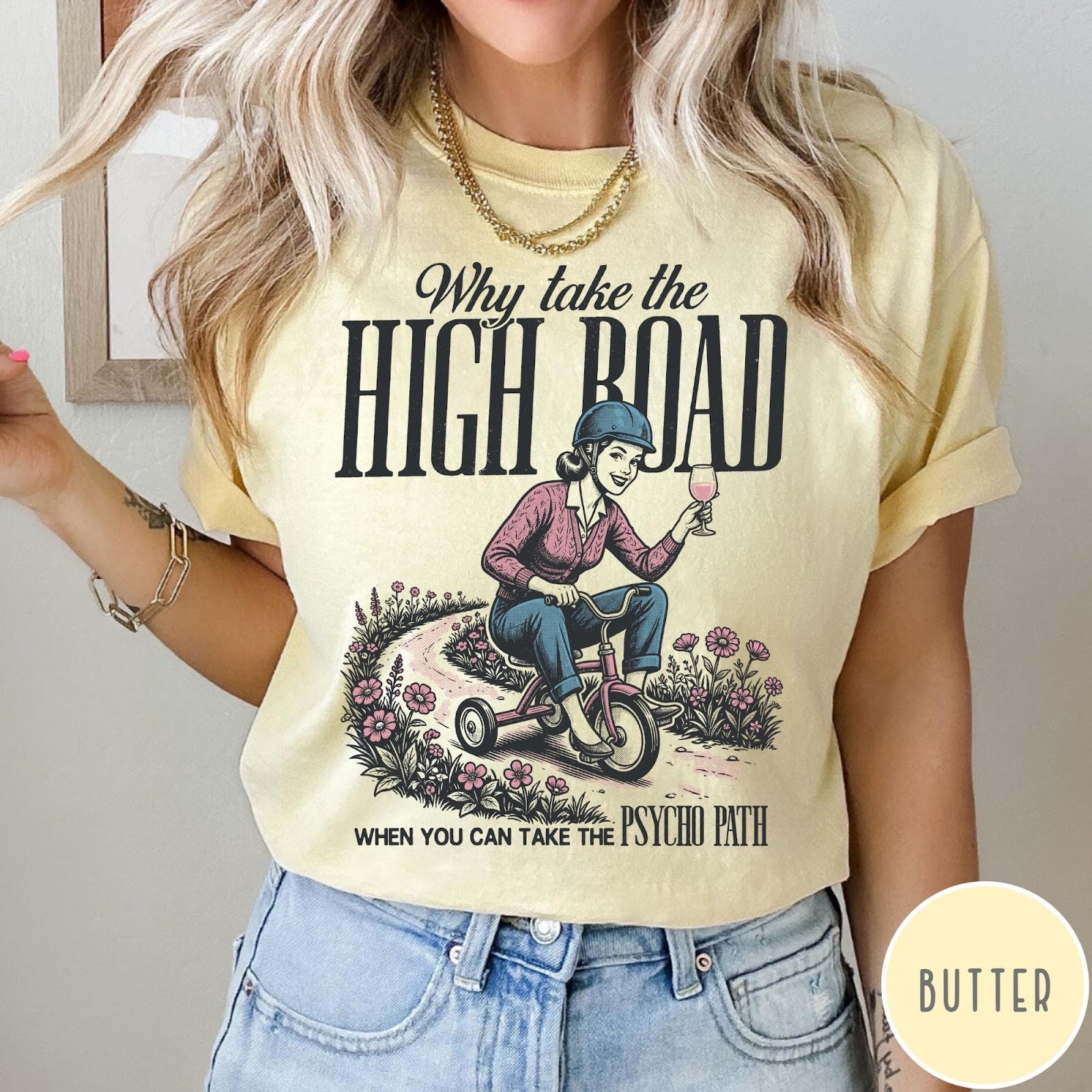 Comfort Colors tee in Butter featuring vintage style graphic of a woman riding a tricycle with wine