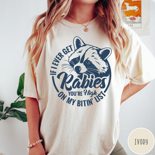 Comfort Colors tee in Ivory featuring screen print style graphic of a raccoon with funny rabies text
