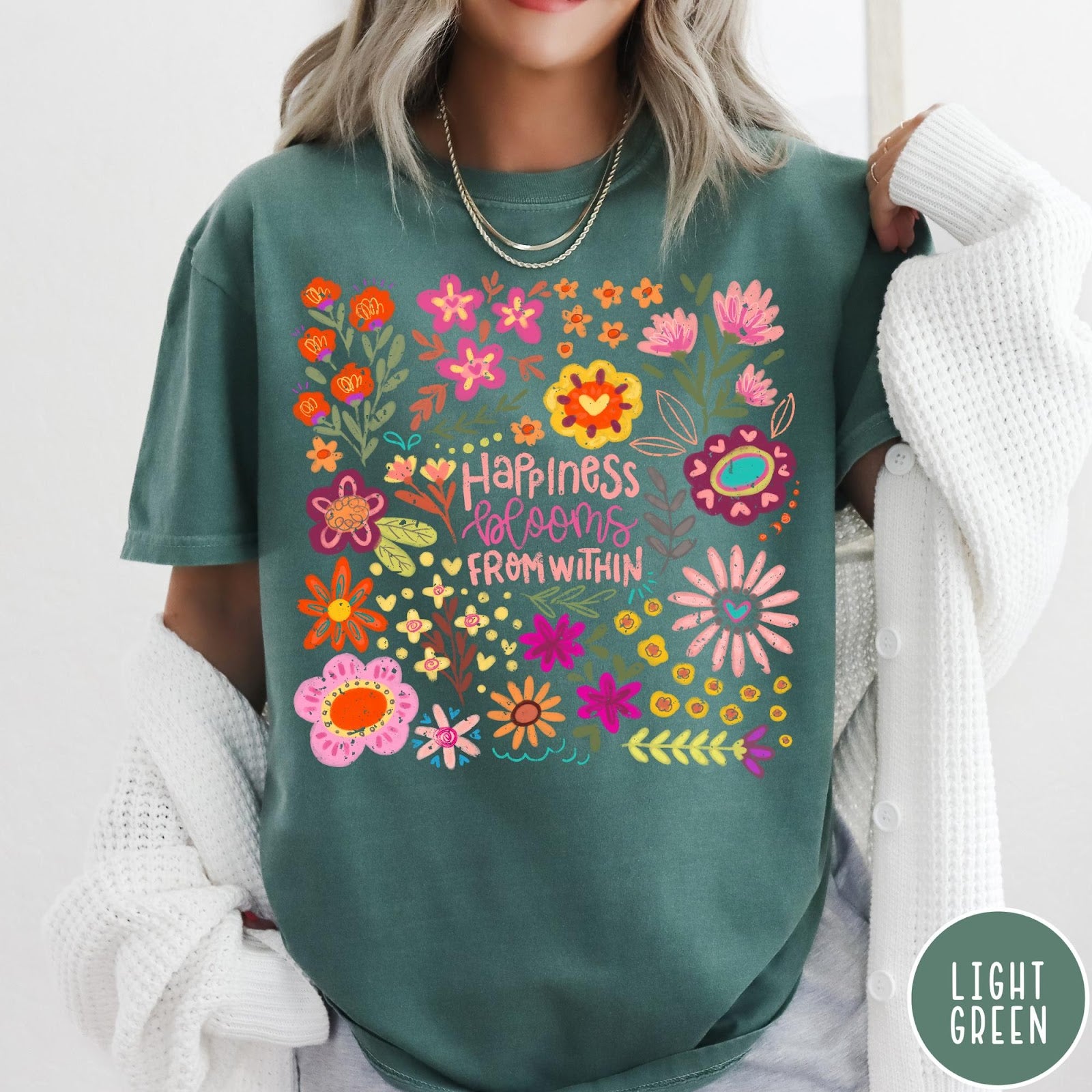 Comfort Colors tee in Light Green featuring floral wildflowers design with Happiness Blooms Within text graphic description