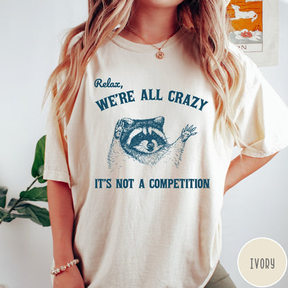 Comfort Colors tee in Ivory featuring screen print style graphic of a raccoon with text Relax We Are All Crazy