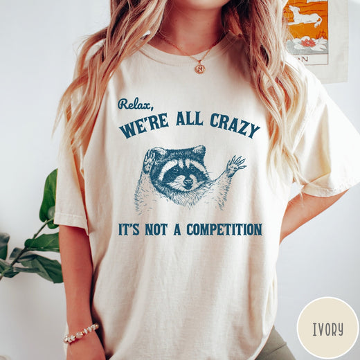 Comfort Colors tee in Ivory featuring screen print style graphic of a raccoon with text Relax We Are All Crazy