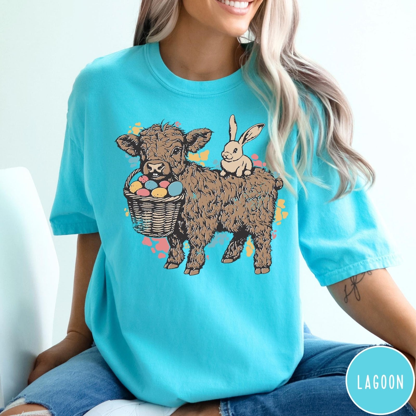 Comfort Colors tee in Lagoon featuring graphic style illustration of a Highland cow with bunny and eggs