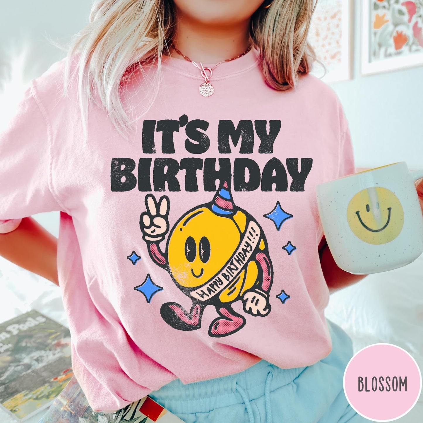 Comfort Colors tee in Blossom featuring retro birthday mascot graphic with peace sign and party hat