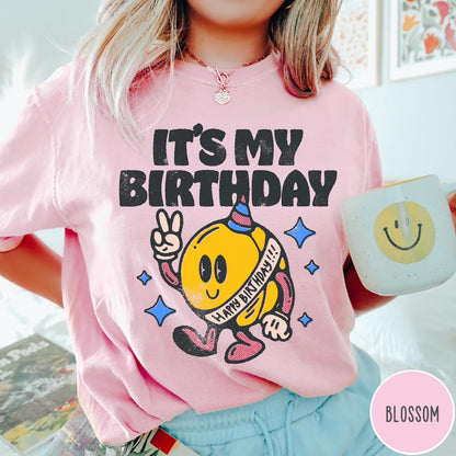 Comfort Colors tee in Blossom featuring retro birthday mascot graphic with peace sign and party hat