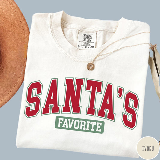 Comfort Colors tee in Ivory featuring collegiate style Santa's Favorite Christmas graphic with red and green text