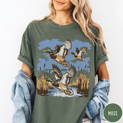 Comfort Colors tee in Moss featuring vintage style mallard ducks flying over a marshy pond graphic
