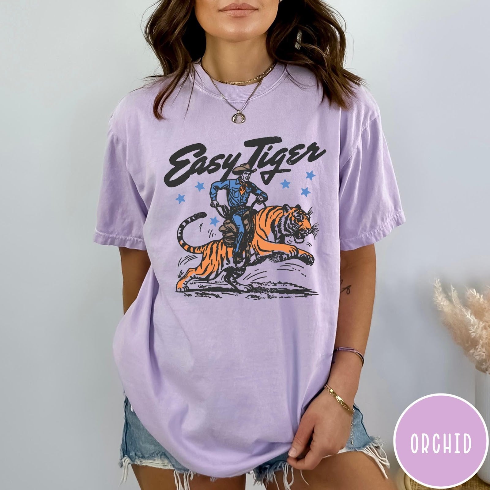 Comfort Colors tee in Orchid featuring western graphic style cowboy riding a tiger with blue stars