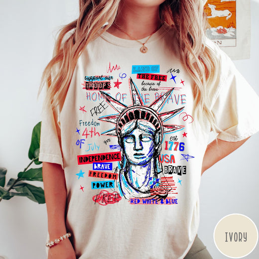 Comfort Colors tee in Ivory featuring grunge style Statue of Liberty graphic with patriotic red and blue text