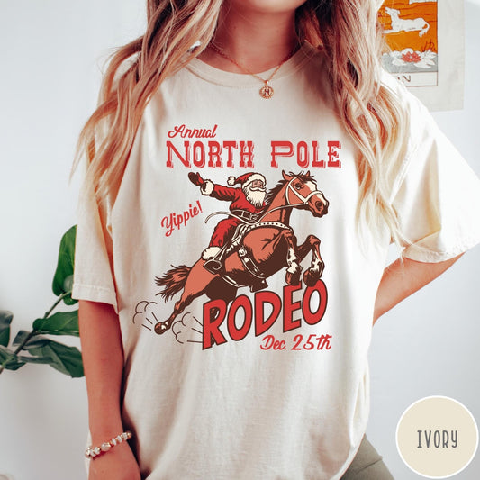 Comfort Colors tee in Ivory featuring vintage style graphic of Santa Claus riding a bucking rodeo horse