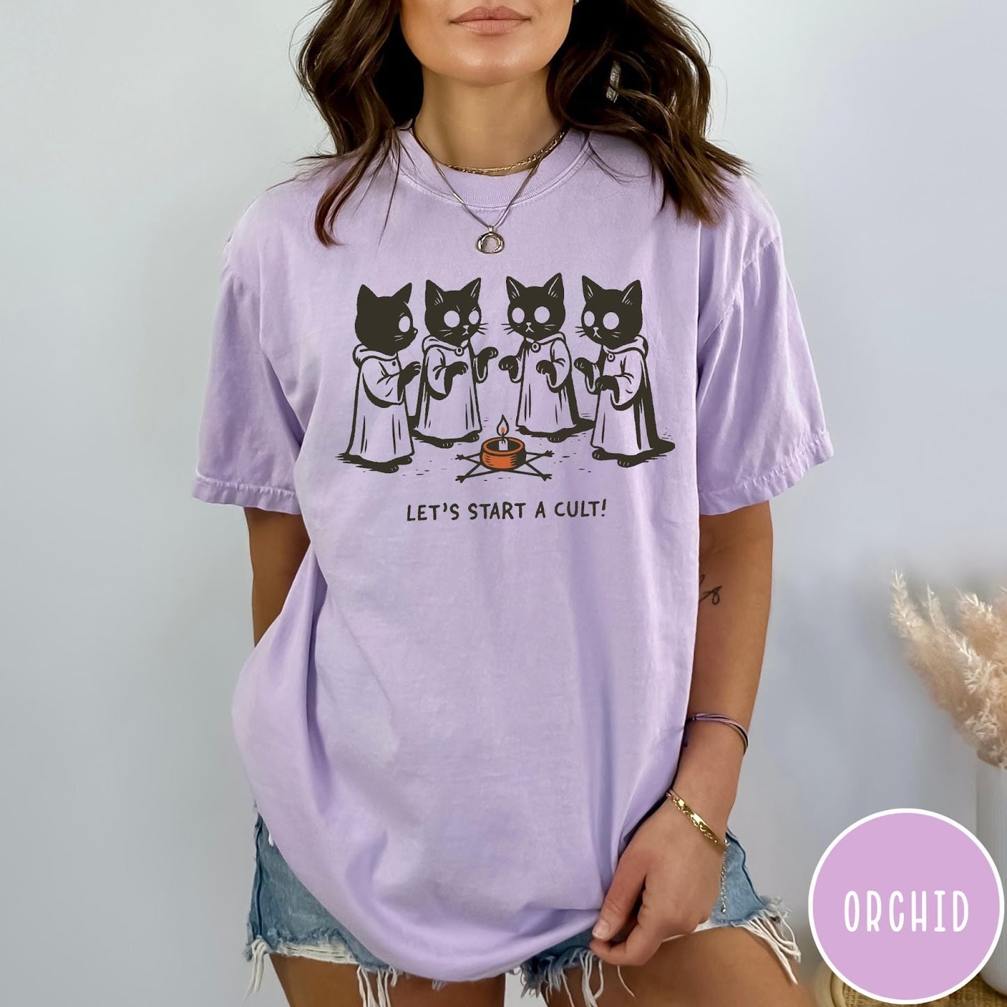 Comfort Colors tee in Orchid featuring illustrated style graphic of four cats in robes around a candle