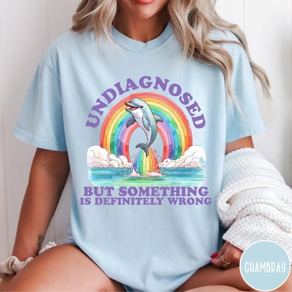 Comfort Colors tee in Chambray featuring graphic style illustration of a dolphin jumping through a colorful rainbow