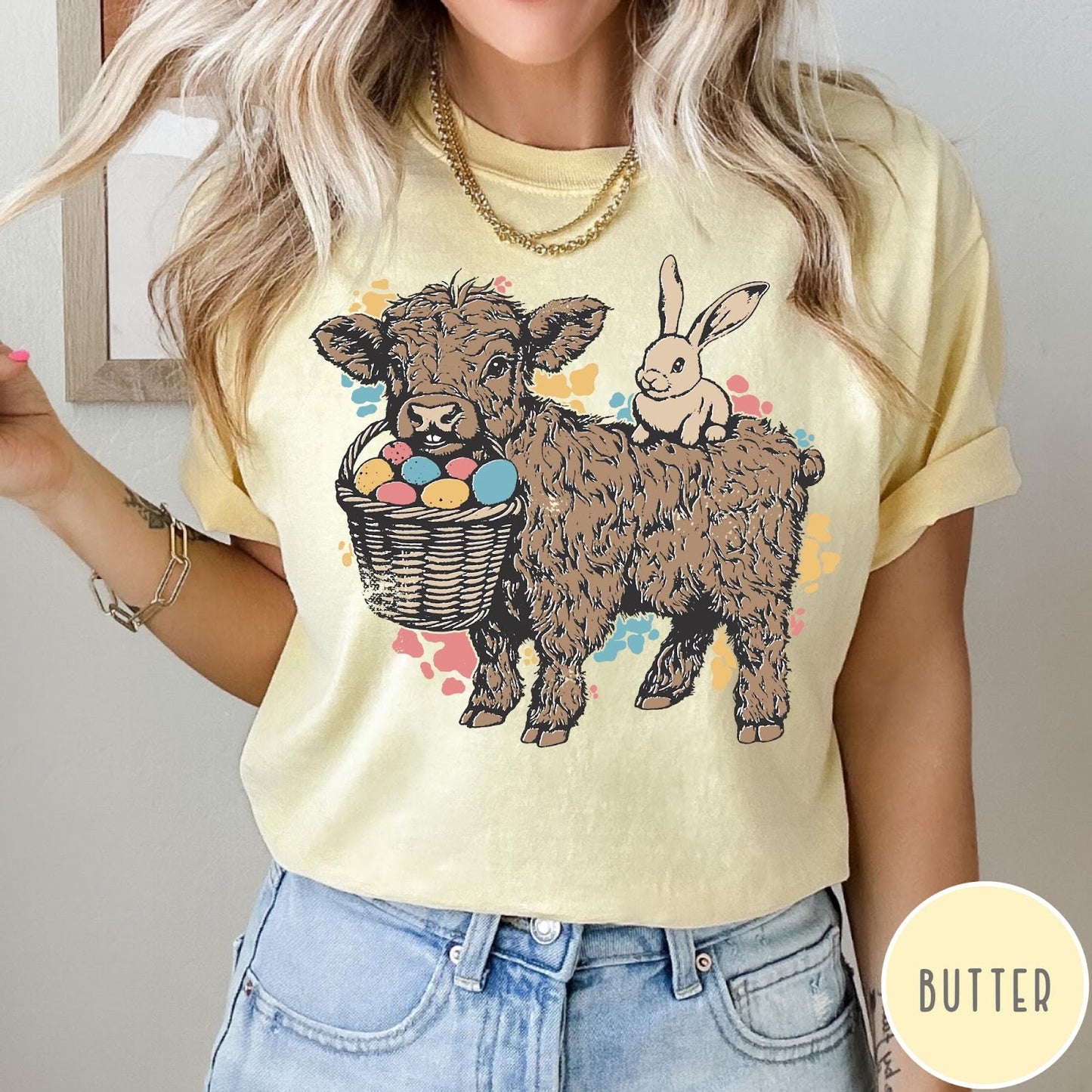 Comfort Colors tee in Butter featuring graphic style Highland cow and bunny with an Easter egg basket