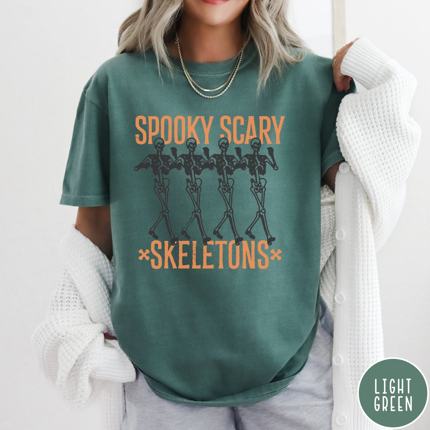 Comfort Colors tee in Light Green featuring dancing skeletons graphic with Spooky Scary Skeletons text in orange