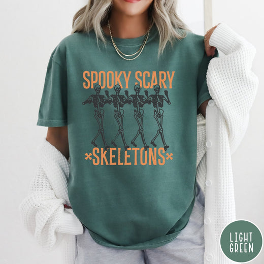 Comfort Colors tee in Light Green featuring dancing skeletons graphic with Spooky Scary Skeletons text in orange
