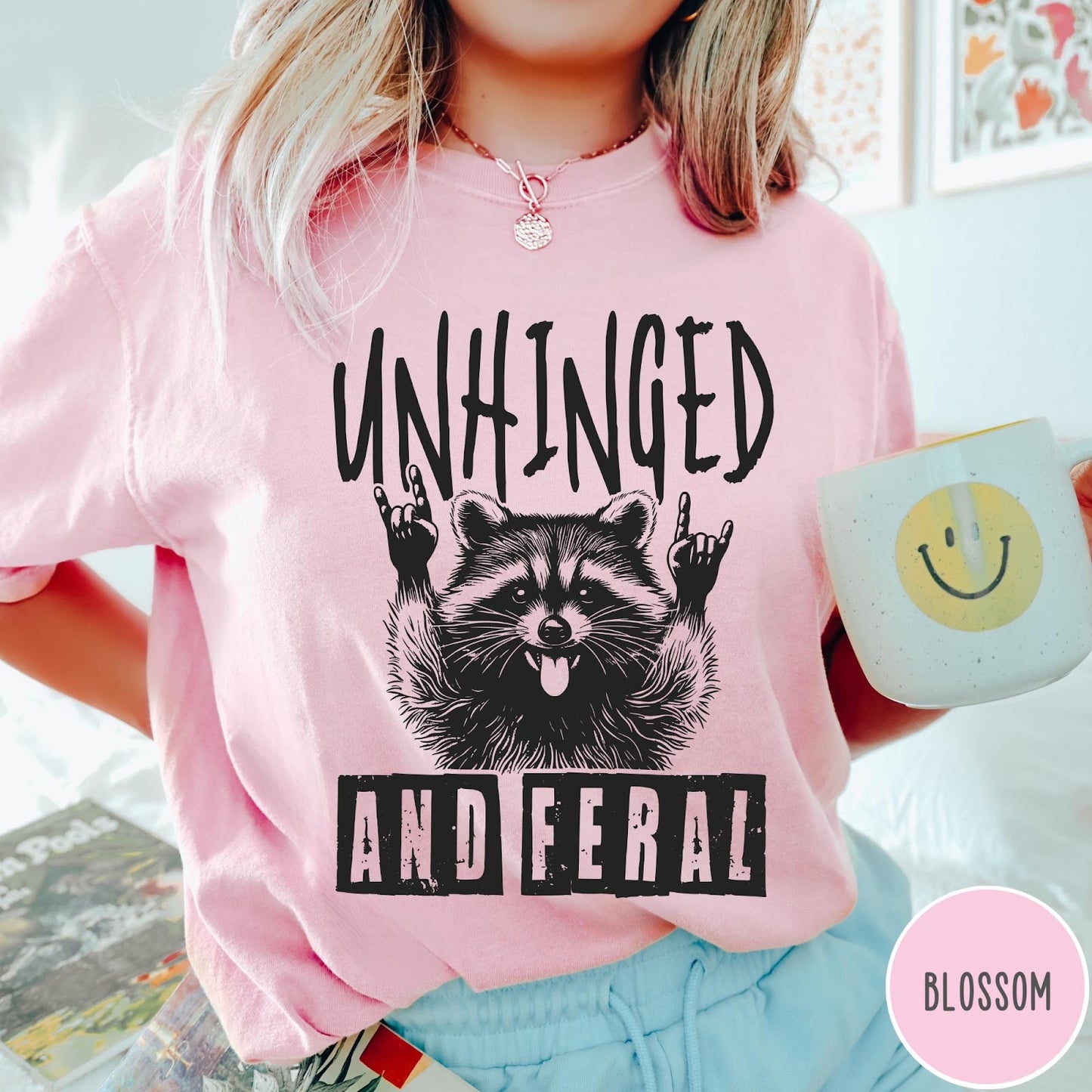 Comfort Colors tee in Blossom featuring graphic style raccoon with tongue out and rock and roll hands