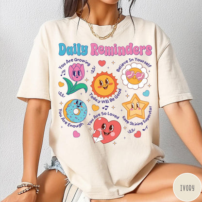 Comfort Colors tee in Ivory featuring retro mascot design with daily affirmations and colorful cartoon characters