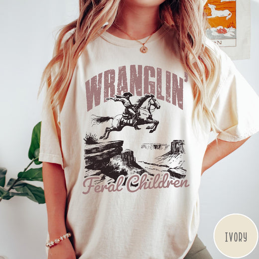 Comfort Colors tee in Ivory featuring western style graphic of a cowboy on horseback jumping a canyon