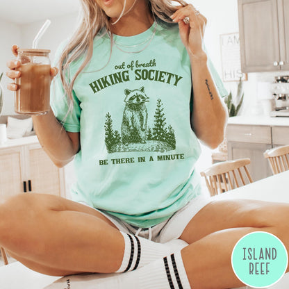Comfort Colors tee in Island Reef featuring outdoor style graphic of a raccoon standing in the forest