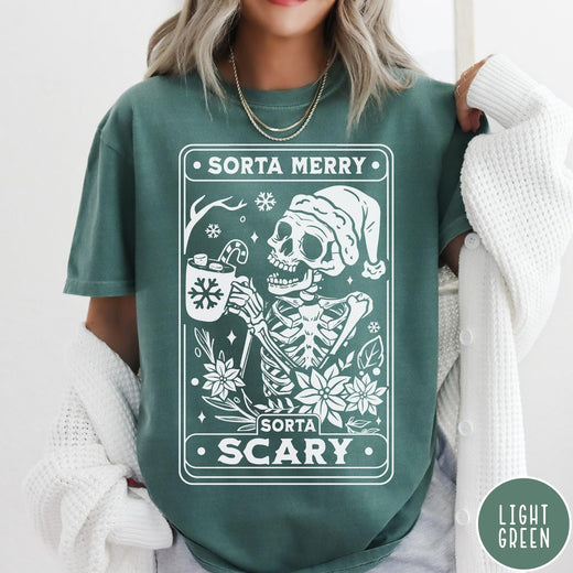 Comfort Colors tee in Light Green featuring graphic design of a skeleton in a Santa hat holding cocoa