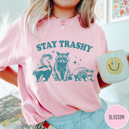 Comfort Colors tee in Blossom featuring graphic style raccoon, skunk, and opossum wearing sunglasses with Stay Trashy text