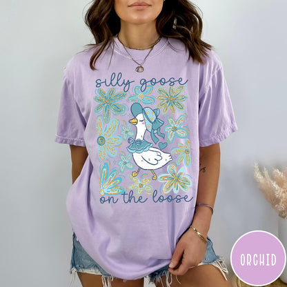 Comfort Colors tee in Orchid featuring whimsical graphic style with a goose wearing a bonnet and floral border