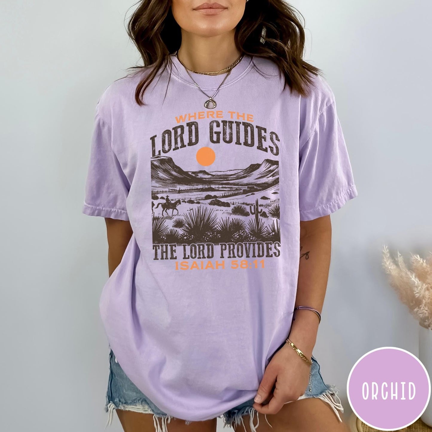 Comfort Colors tee in Orchid featuring desert landscape graphic with a rider and sun design.