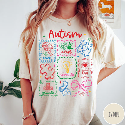 Comfort Colors tee in Ivory featuring coquette style autism awareness graphic with puzzle pieces and colorful icons