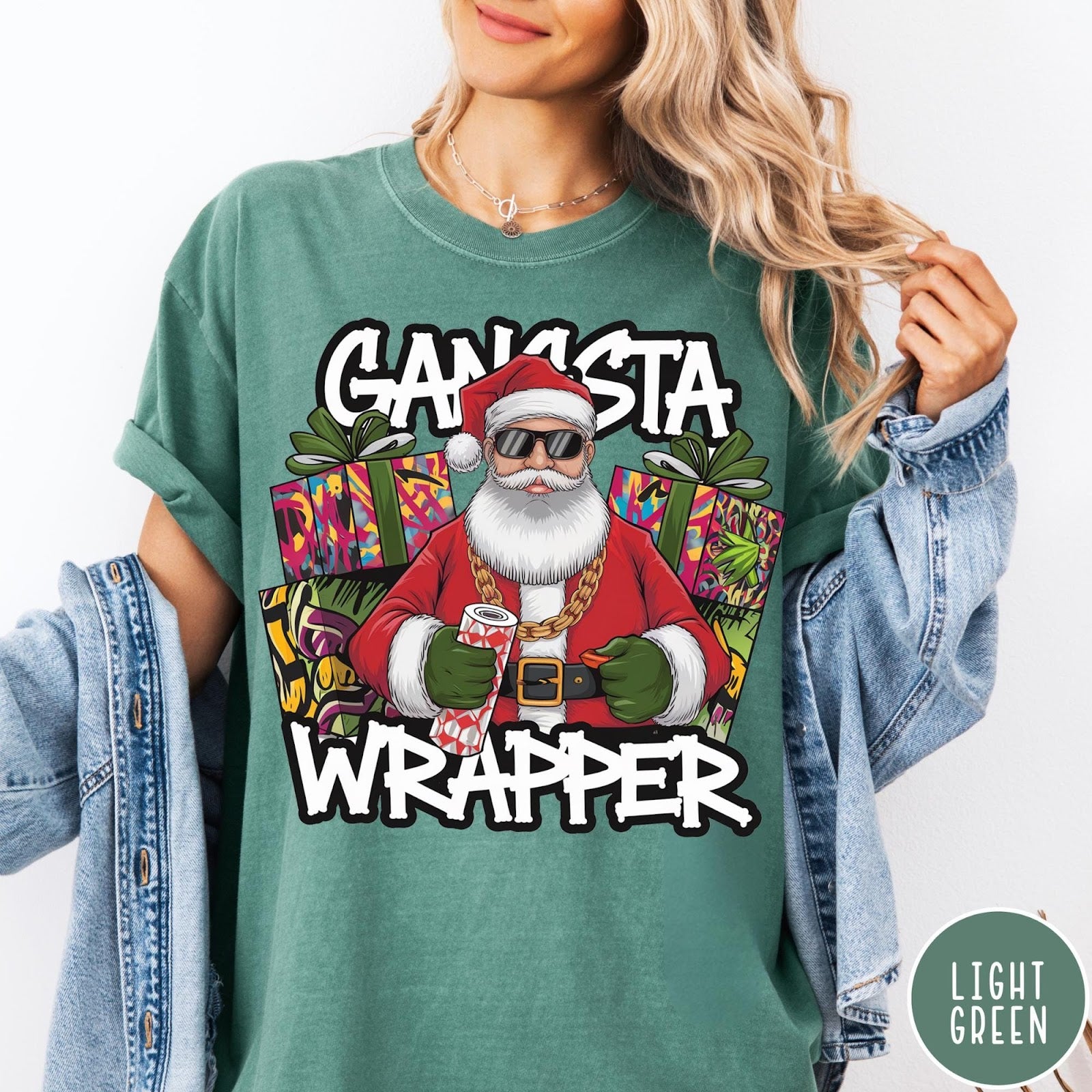 Comfort Colors tee in Light Green featuring cartoon style Santa Claus wearing sunglasses and gold chain holding wrapping paper