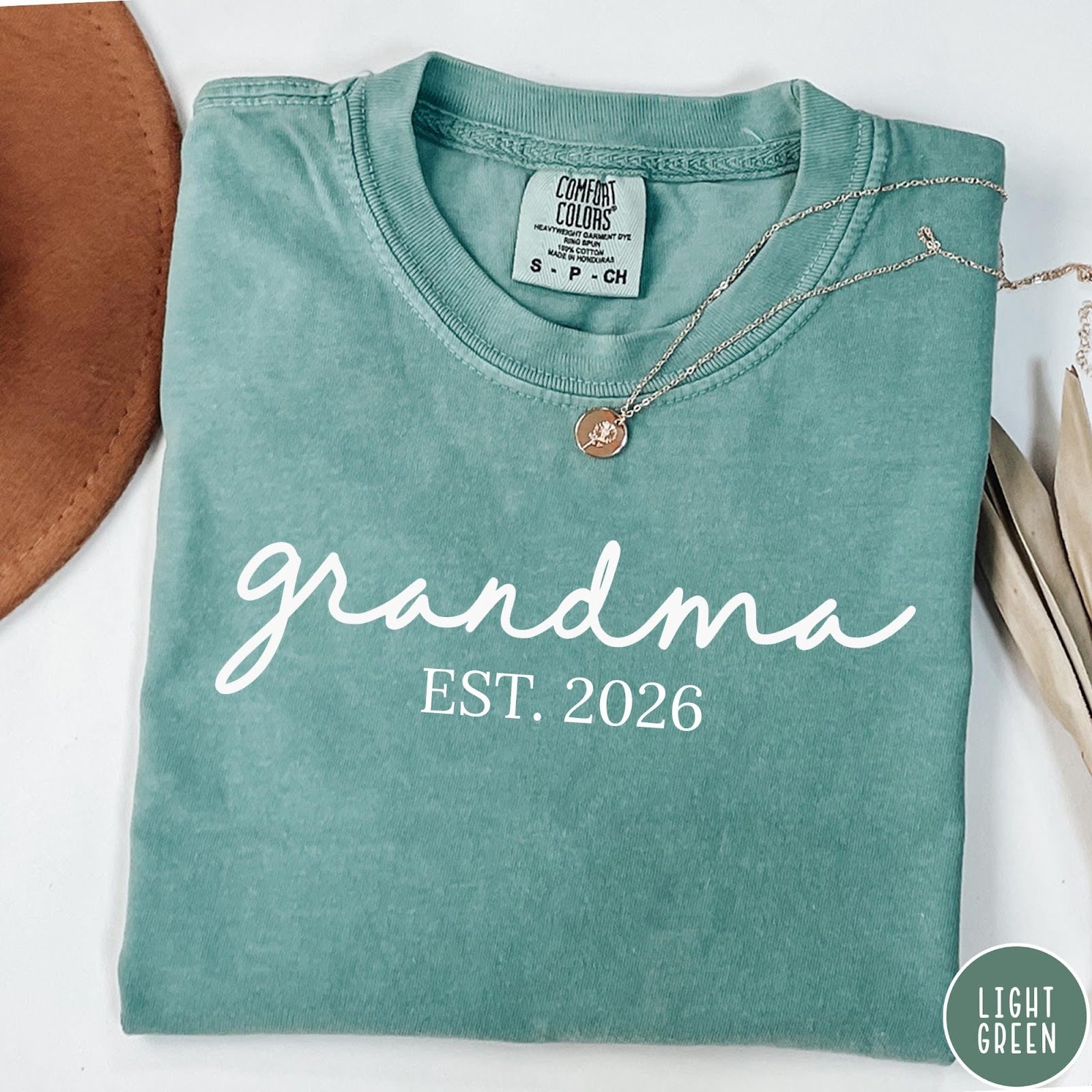 Comfort Colors tee in Light Green featuring cursive Grandma Est 2026 text in a clean white graphic style