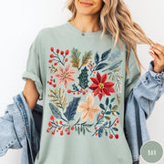 Comfort Colors tee in Bay featuring winter florals graphic with poinsettias, holly leaves, and red berries.