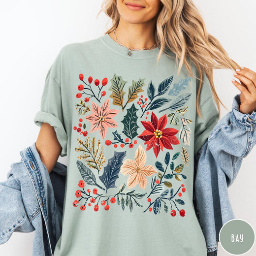 Comfort Colors tee in Bay featuring winter florals graphic with poinsettias, holly leaves, and red berries.