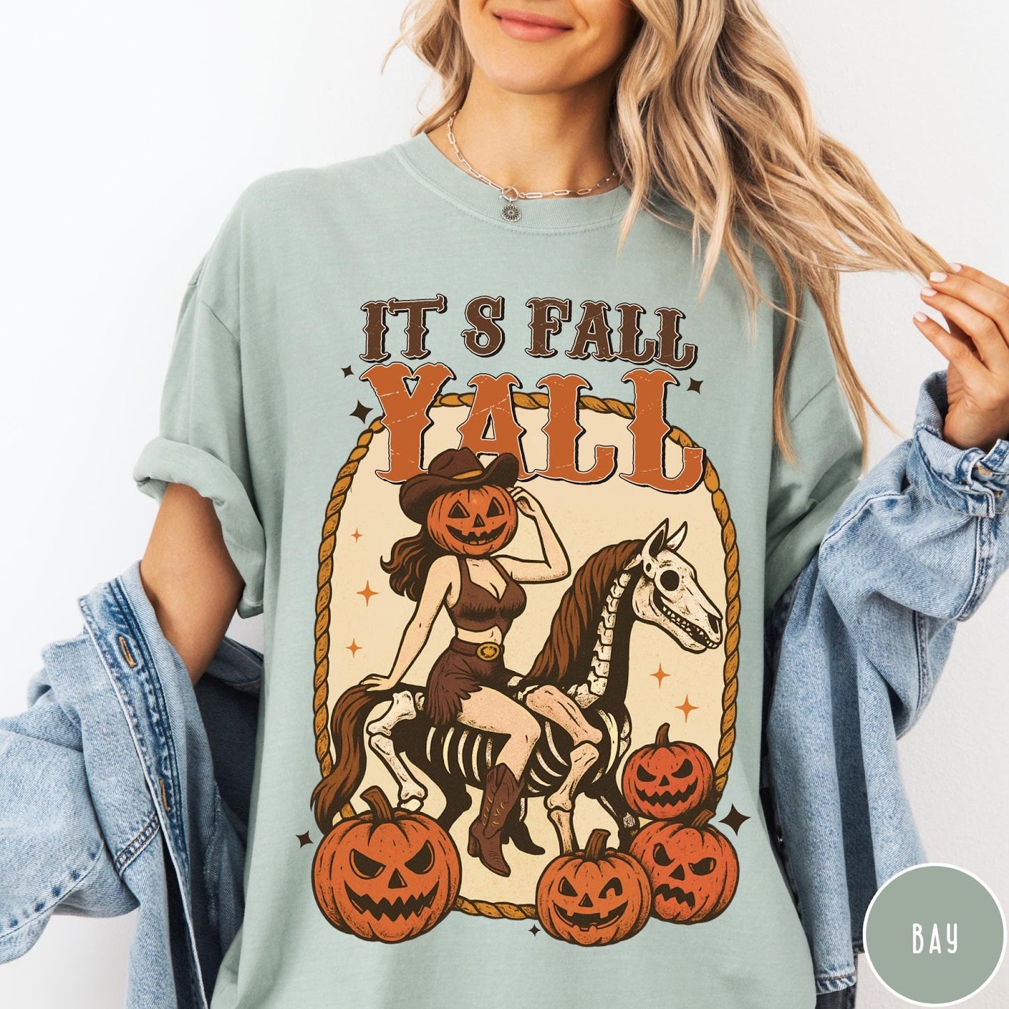 Comfort Colors tee in Bay featuring western graphic of a pumpkin cowgirl riding a skeleton horse with pumpkins