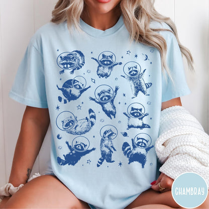 Comfort Colors tee in Chambray featuring whimsical space design with multiple raccoons wearing glass astronaut helmets and stars