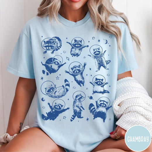 Comfort Colors tee in Chambray featuring whimsical space design with multiple raccoons wearing glass astronaut helmets and stars