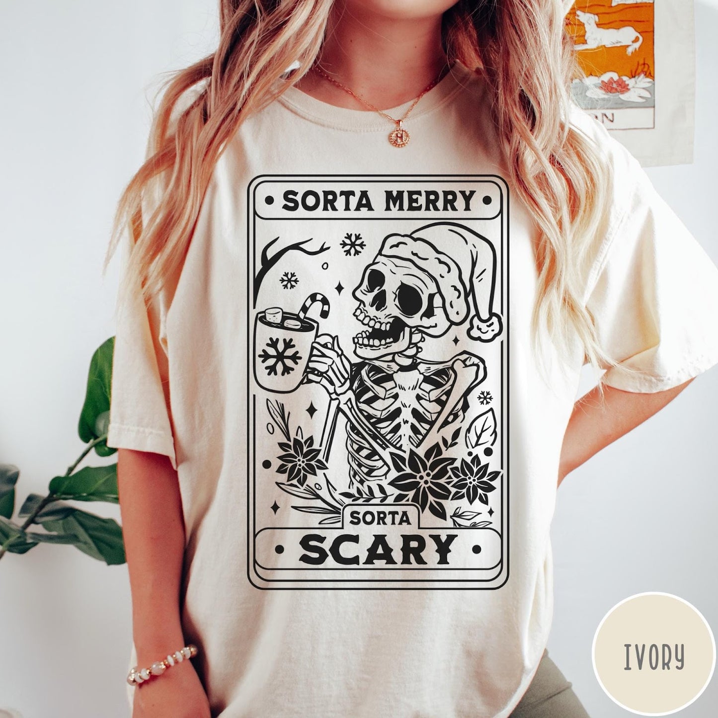 Comfort Colors tee in Ivory featuring graphic design of a skeleton in a Santa hat holding cocoa