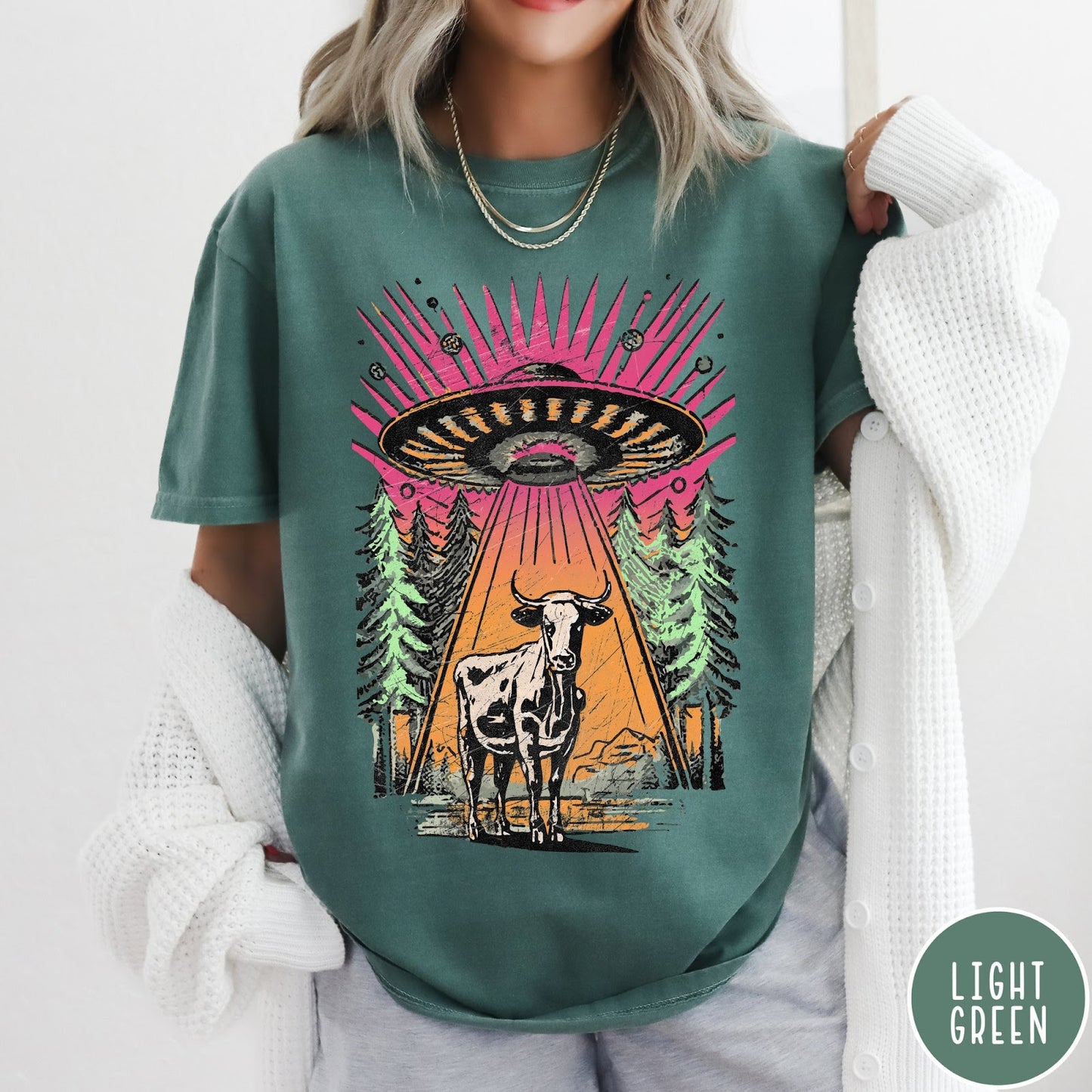 Comfort Colors tee in Light Green featuring graphic style cow being abducted by a UFO in the forest