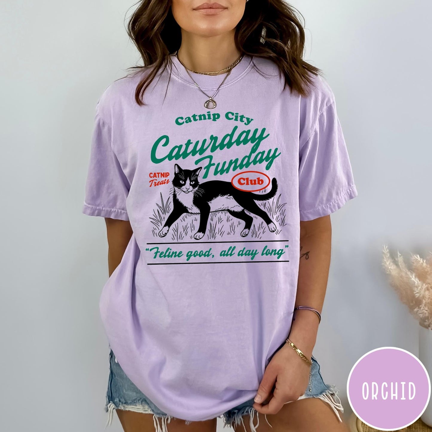 Comfort Colors tee in Orchid featuring vintage style graphic of a tuxedo cat in grass with text