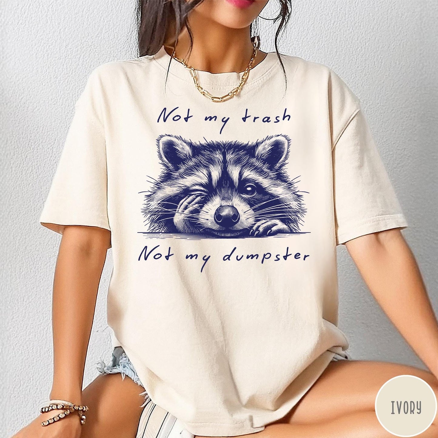 Comfort Colors tee in Ivory featuring graphic illustration of a winking raccoon with text Not My Trash