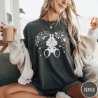 Comfort Colors tee in Pepper featuring line art style upside down bat graphic with surrounding floral elements