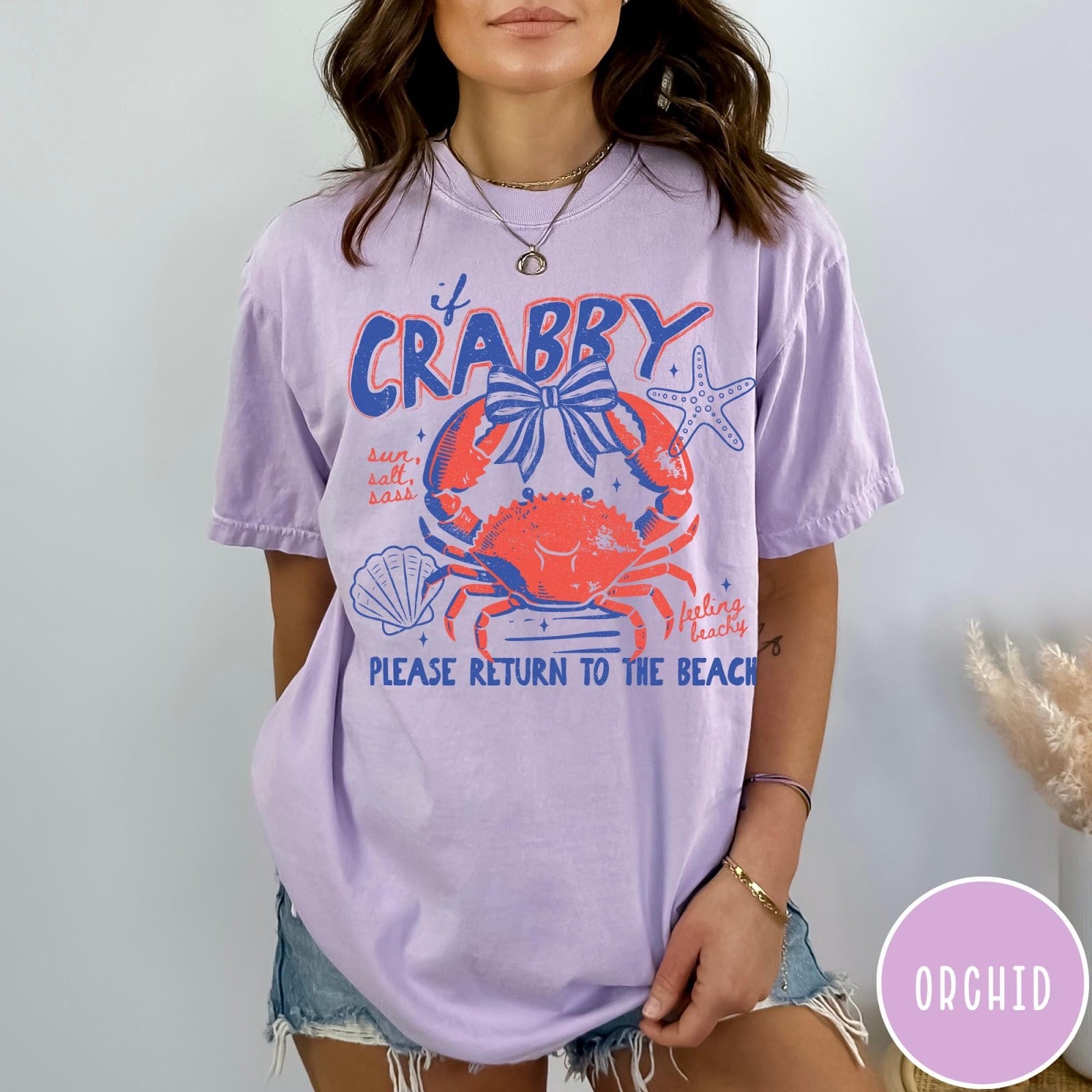 Comfort Colors tee in Orchid featuring coastal graphic design with a crab, bow, starfish, and beach text